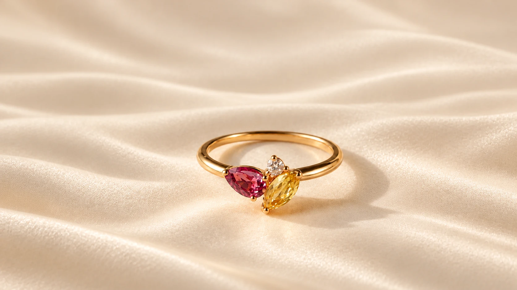 Gold ring with pink and yellow sapphires and a diamond on cream silk